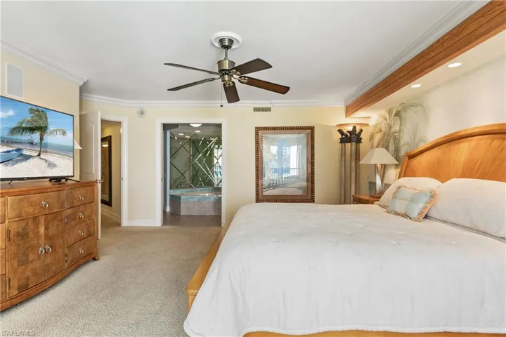 Bedroom with light carpet, ornamental molding, and ceiling fan