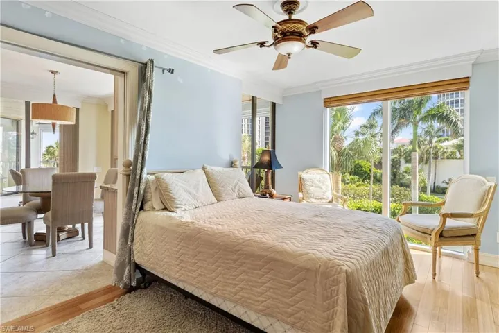 Bedroom with ceiling fan, multiple windows, hardwood / wood-style flooring, and ornamental molding