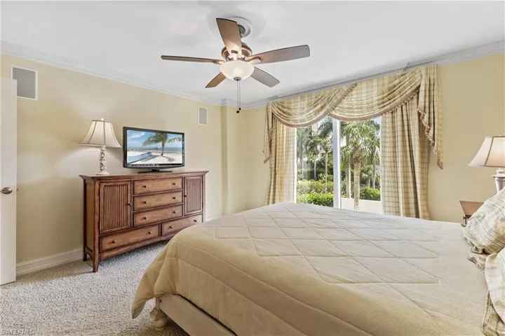 Carpeted bedroom featuring ceiling fan and crown molding