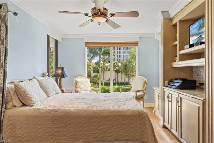Bedroom featuring light hardwood / wood-style floors, crown molding, and ceiling fan