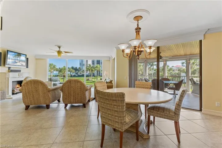 Tiled dining space with ceiling fan with notable chandelier and crown molding