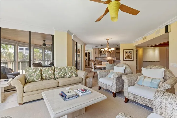 Living room featuring crown molding and ceiling fan with notable chandelier
