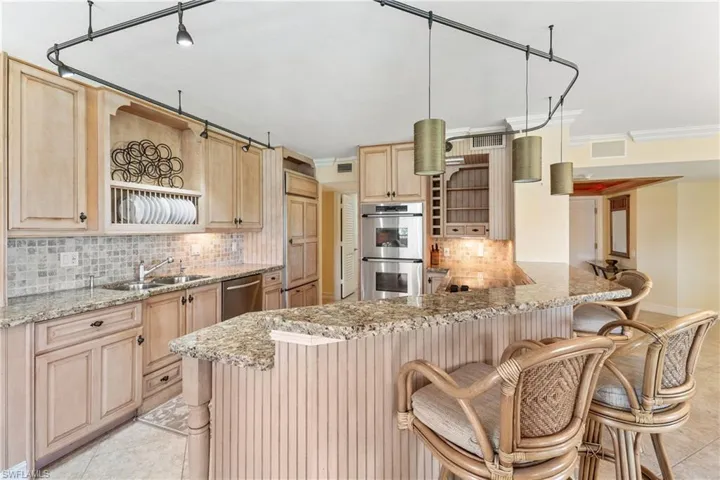 Kitchen with appliances with stainless steel finishes, tasteful backsplash, light tile floors, and a kitchen bar