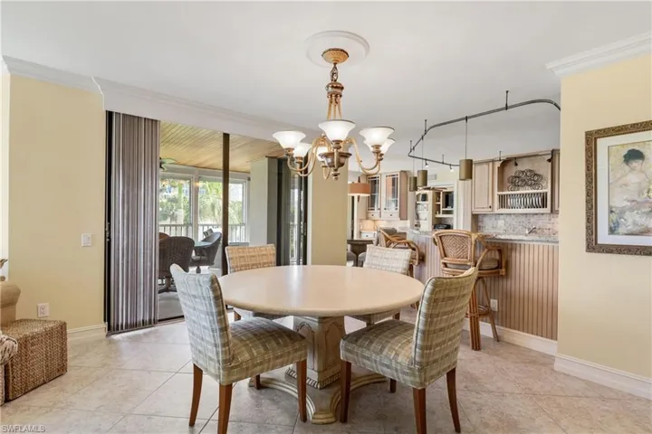 Dining room featuring ornamental molding, a chandelier, and light tile floors
