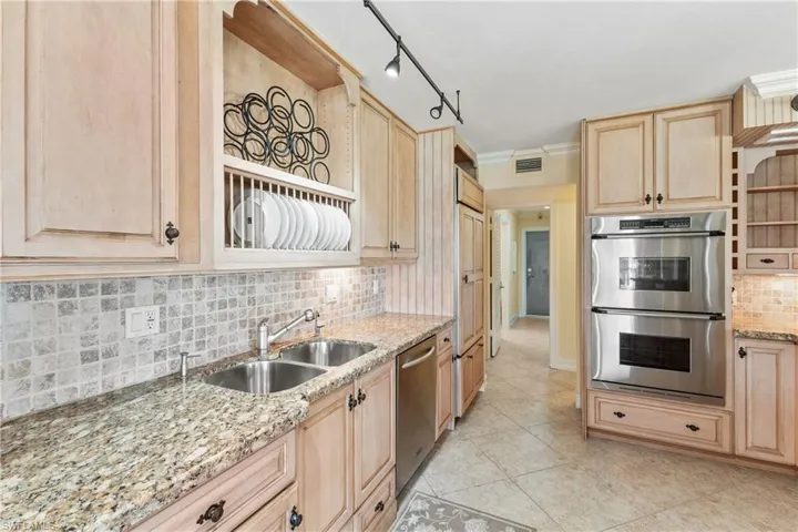 Kitchen featuring stainless steel appliances, backsplash, rail lighting, sink, and light tile flooring