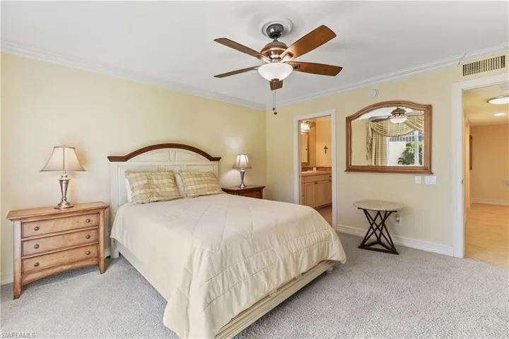 Carpeted bedroom featuring ceiling fan, connected bathroom, and ornamental molding