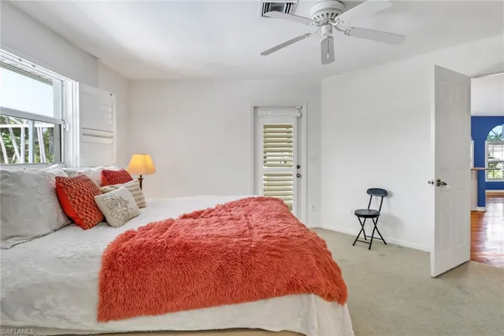 Carpeted bedroom with multiple windows and ceiling fan