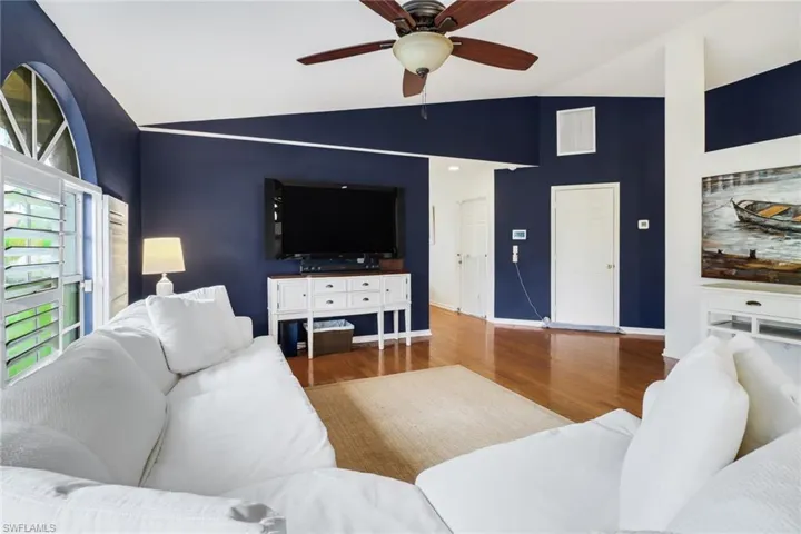 Living room with ceiling fan, hardwood / wood-style flooring, and high vaulted ceiling