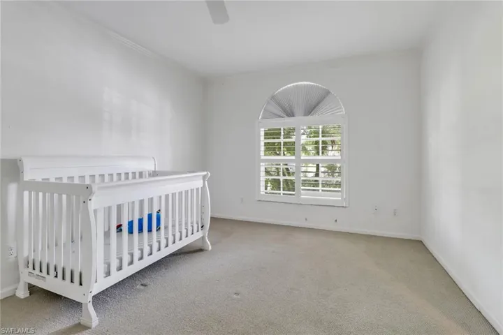 Unfurnished bedroom featuring ceiling fan, carpet floors, a crib, and crown molding
