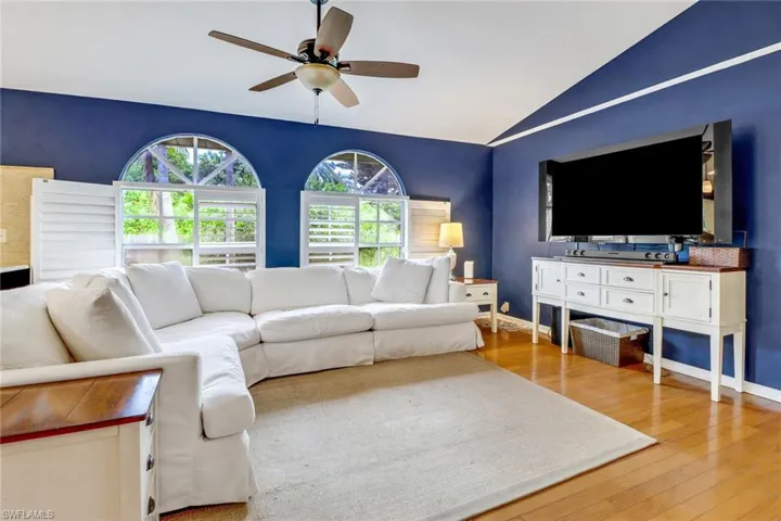 Living room with lofted ceiling, wood-type flooring, and ceiling fan