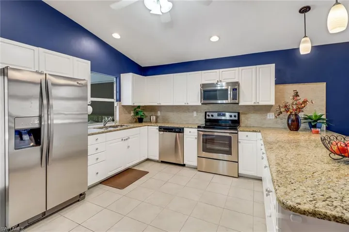 Kitchen featuring stainless steel appliances, sink, hanging light fixtures, backsplash, and ceiling fan