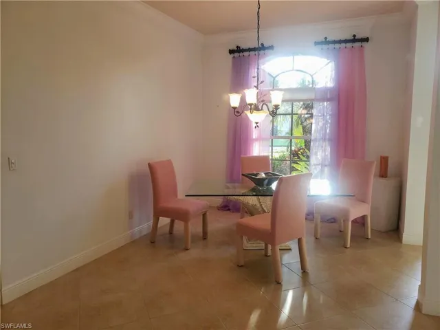 Tiled dining space with a chandelier and crown molding