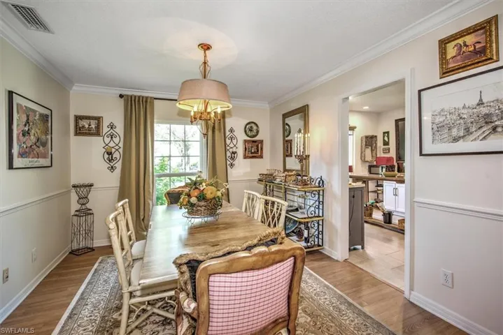 Dining space featuring an inviting chandelier, light hardwood / wood-style flooring, and crown molding