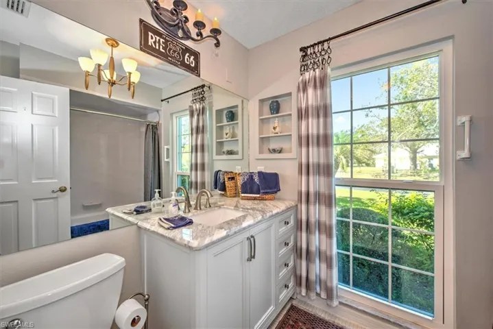 Bathroom featuring a notable chandelier, vanity, and toilet