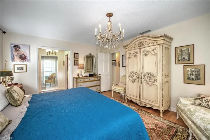Bedroom featuring dark hardwood / wood-style floors, a textured ceiling, and a notable chandelier