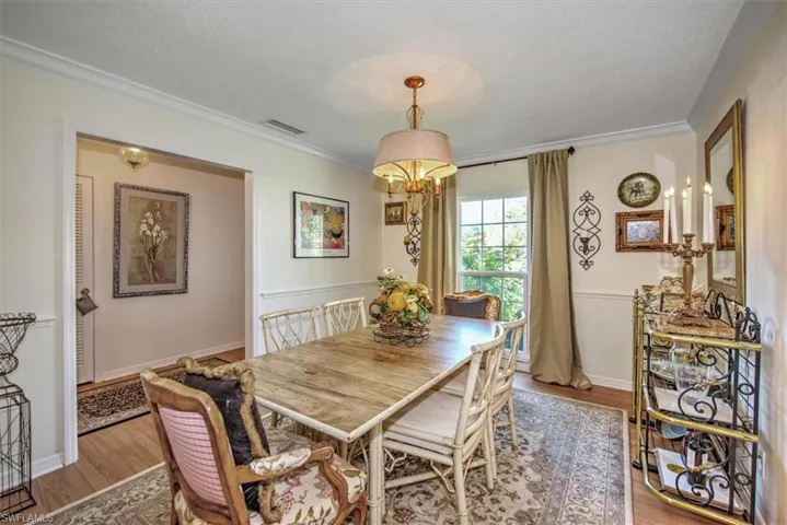 Dining room featuring ornamental molding, light wood-type flooring, and a textured ceiling