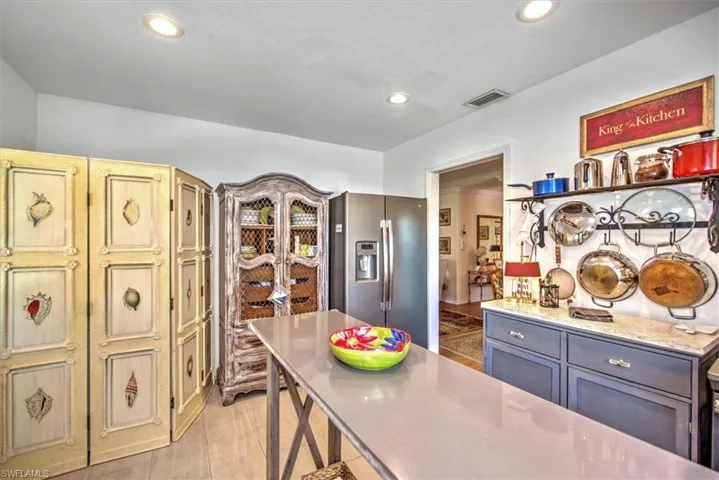 Kitchen with light wood-type flooring, gray cabinetry, stainless steel fridge with ice dispenser, and light stone counters