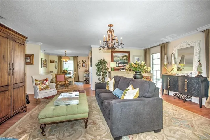 Living room featuring a textured ceiling, ornamental molding, an inviting chandelier, and light hardwood / wood-style flooring