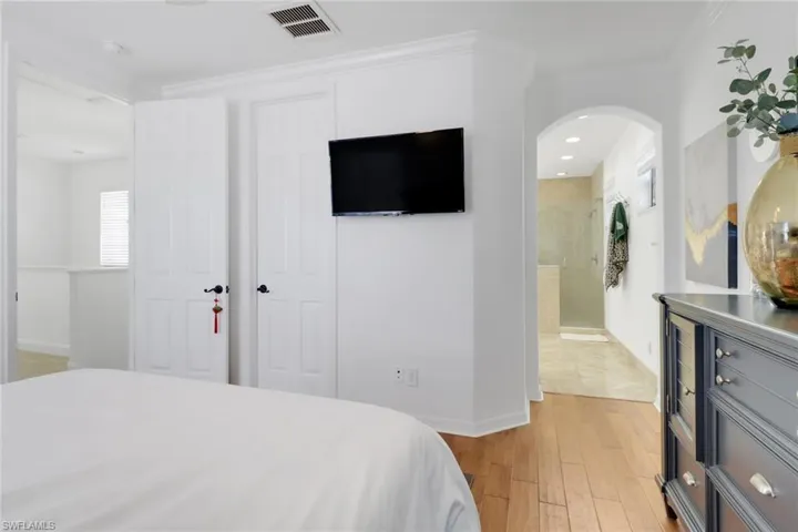 Bedroom featuring connected bathroom, light hardwood / wood-style floors, and crown molding