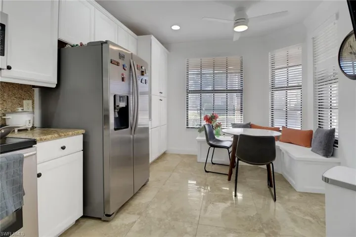 Kitchen with white cabinetry, electric range, ceiling fan, tasteful backsplash, and stainless steel refrigerator with ice dispenser