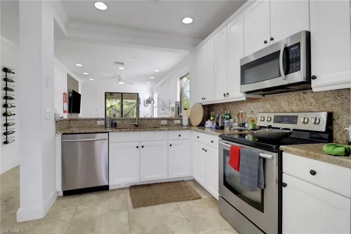 Kitchen with white cabinetry, sink, backsplash, appliances with stainless steel finishes, and ornamental molding
