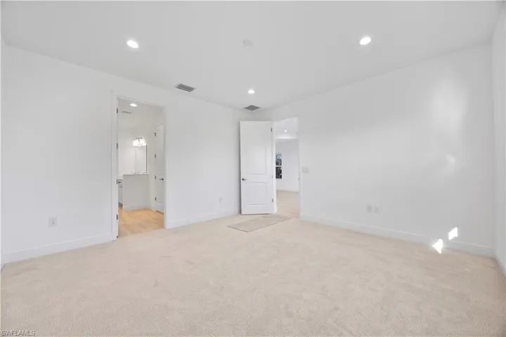 Unfurnished bedroom featuring recessed lighting, light colored carpet, and connected bathroom