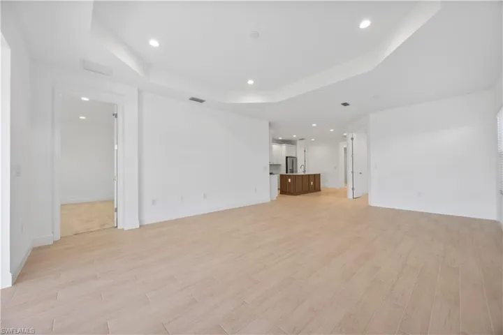 Unfurnished living room featuring light wood-style flooring, a raised ceiling, and recessed lighting