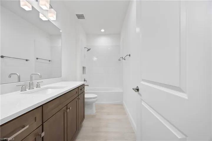 Full bath featuring vanity, bathing tub / shower combination, light wood-style floors, and recessed lighting