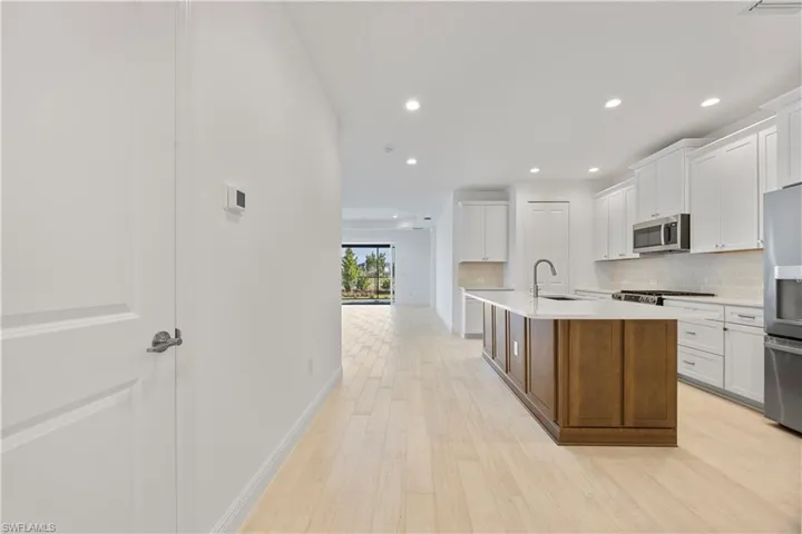 Dual tone kitchen with a center island with sink, dual tone cabinetry, light wood-style floors, recessed lighting, and stainless steel appliances