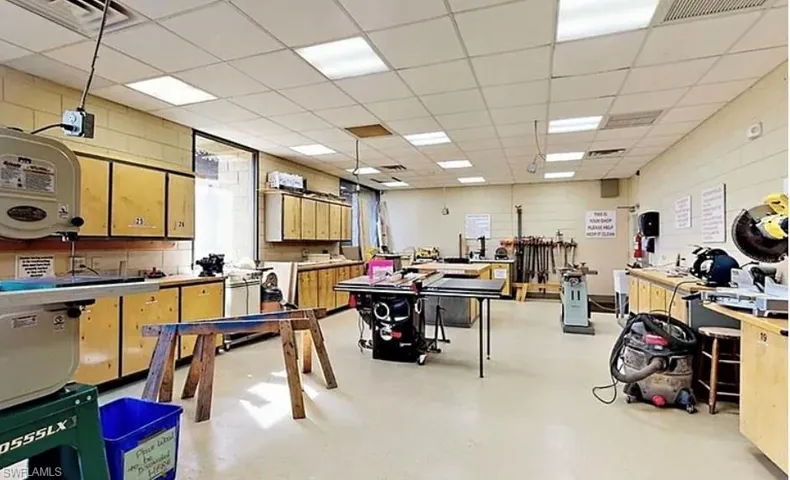 Recreation room with concrete floors, a paneled ceiling, and a workshop area
