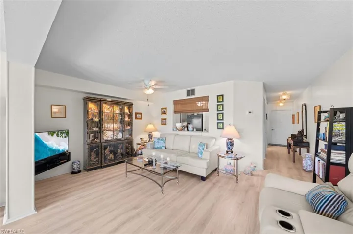 Living area with wood finished floors, a textured ceiling, and a ceiling fan