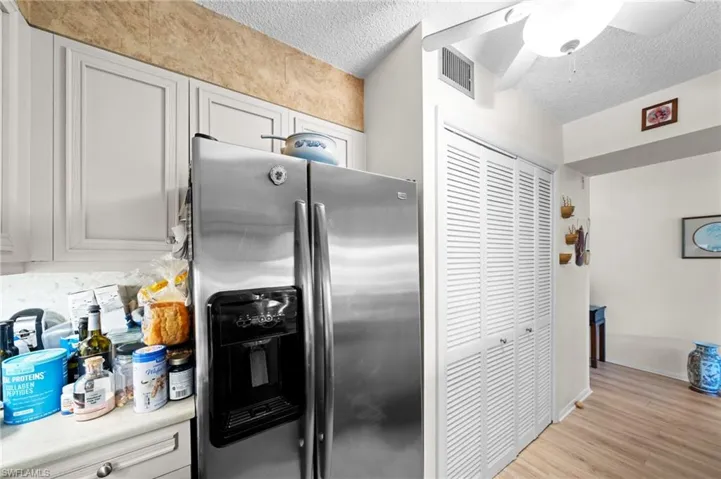 Kitchen featuring stainless steel fridge with ice dispenser, a textured ceiling, light wood-type flooring, ceiling fan, and light countertops