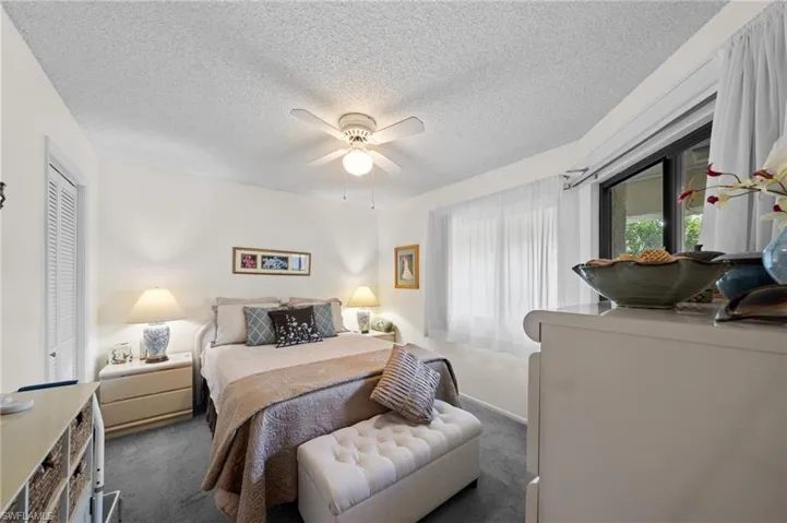 Bedroom featuring carpet flooring, a textured ceiling, and ceiling fan