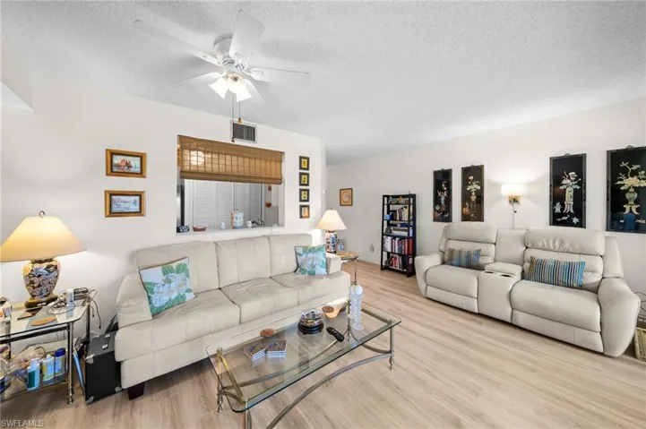 Living room featuring wood finished floors, a textured ceiling, and ceiling fan