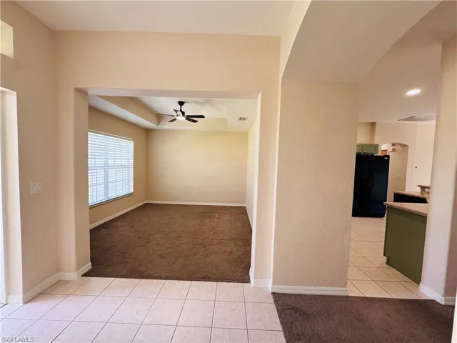 Spare room featuring light carpet, arched walkways, ceiling fan, and light tile patterned flooring