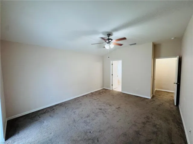Unfurnished bedroom with carpet, lofted ceiling, and a ceiling fan