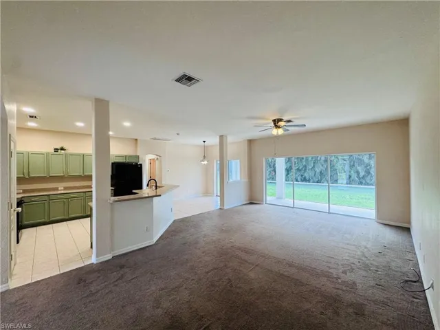 Unfurnished living room with light colored carpet, a ceiling fan, and recessed lighting