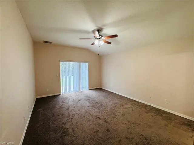 Unfurnished room with a ceiling fan and dark colored carpet