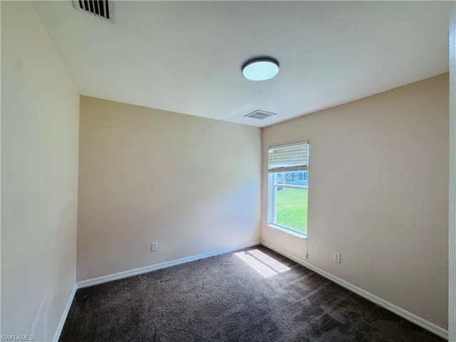 Carpeted spare room featuring baseboards