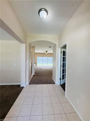 Hallway with carpet floors, arched walkways, and tile patterned floors