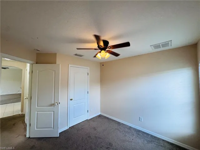 Unfurnished bedroom featuring dark colored carpet and a ceiling fan