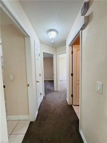 Hall featuring a textured ceiling and light carpet