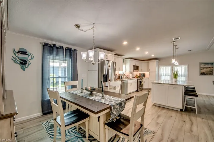 Kitchen featuring stainless steel appliances, tasteful backsplash, white cabinetry, a center island, and a kitchen breakfast bar