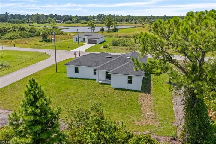 View from above of property with a tree filled landscape and a large body of water