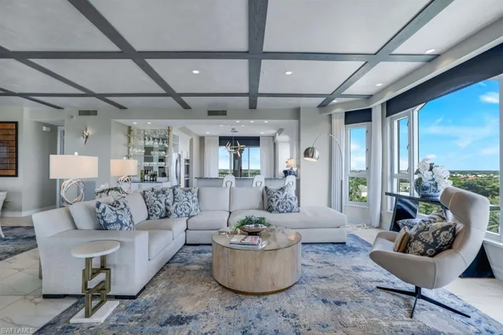 Living room featuring coffered ceiling, a notable chandelier, and beam ceiling