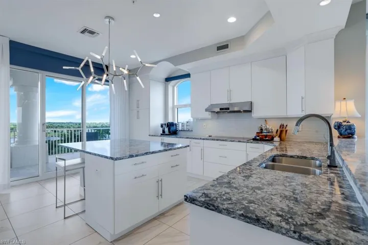 Kitchen featuring pendant lighting, a chandelier, sink, white cabinetry, and a kitchen island