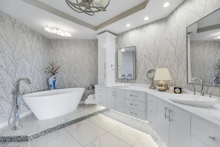 Bathroom with vanity, a tub to relax in, and a raised ceiling