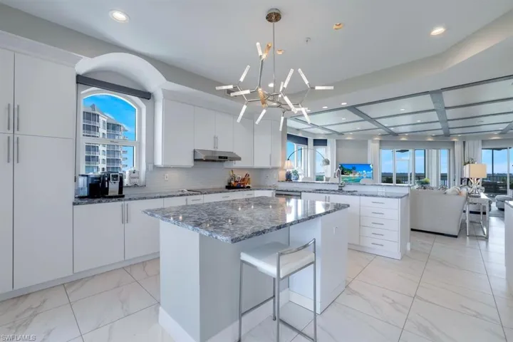Kitchen with stone counters, white cabinetry, tasteful backsplash, and a center island