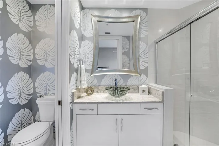 Bathroom featuring walk in shower, vanity, and toilet
