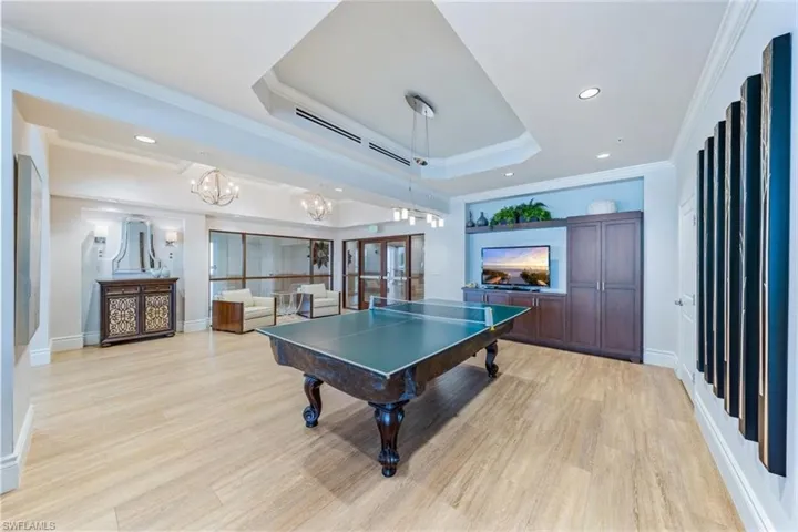 Playroom with light hardwood / wood-style floors, a raised ceiling, and ornamental molding